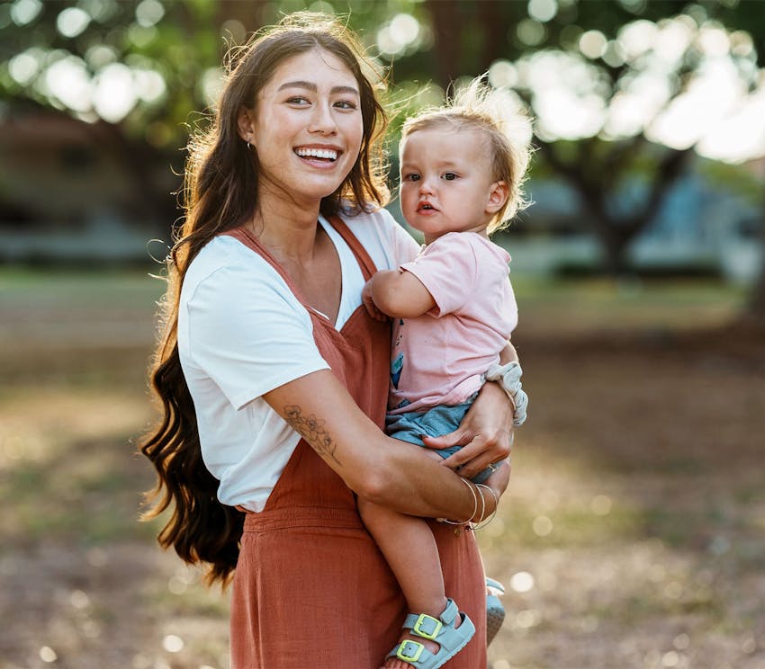 woman smiling and holding her toddler