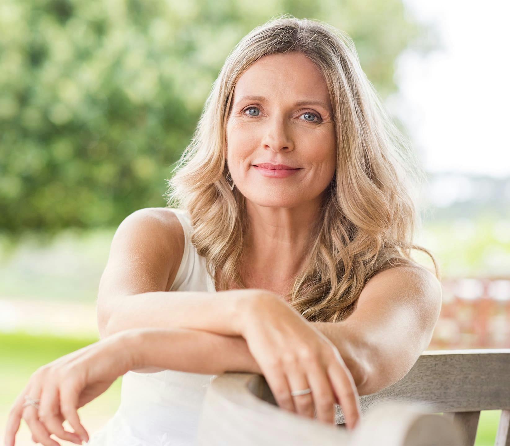 Woman outside with arms crossed smiling