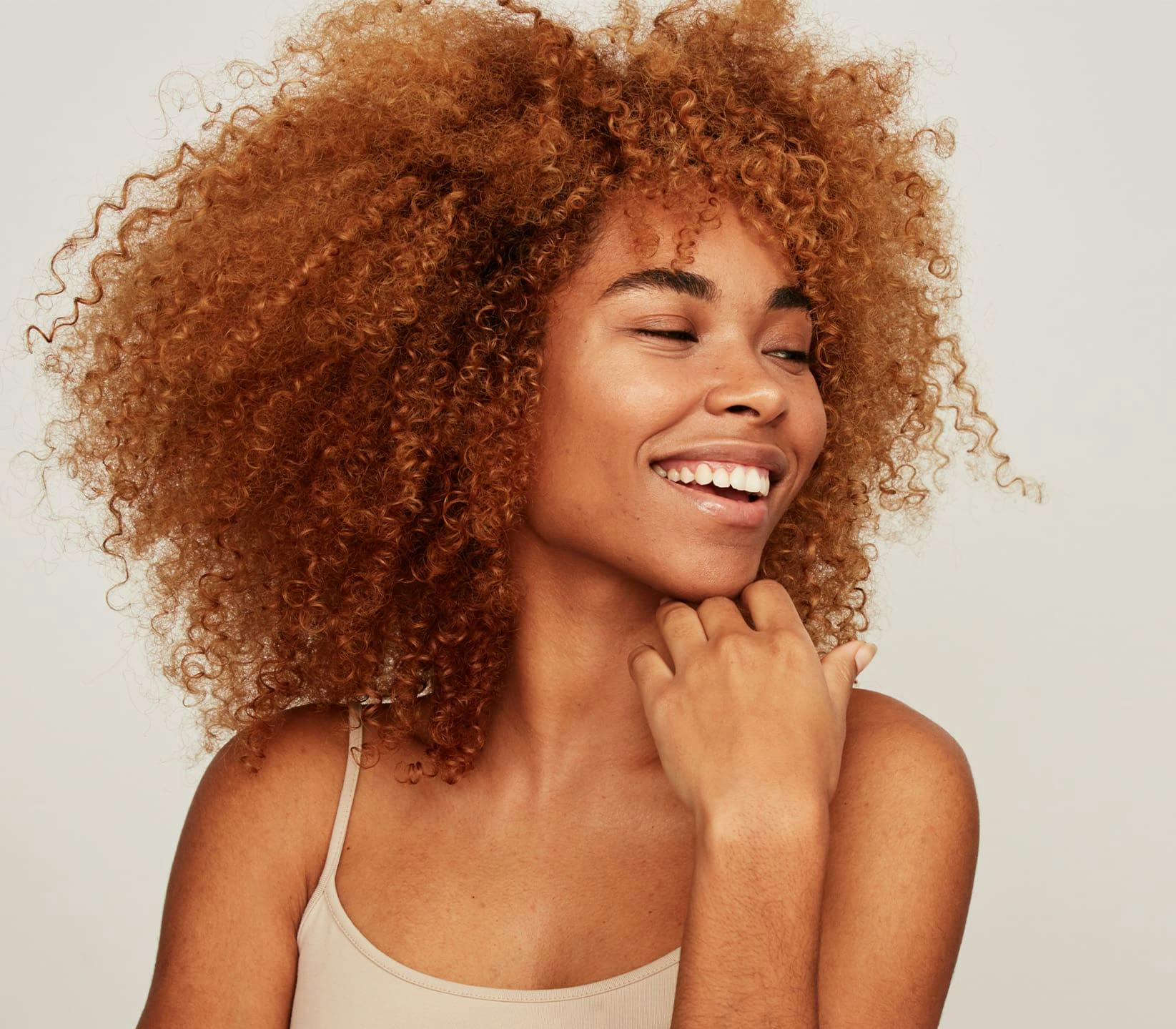 woman with afro smiling and touching her chin with her hand