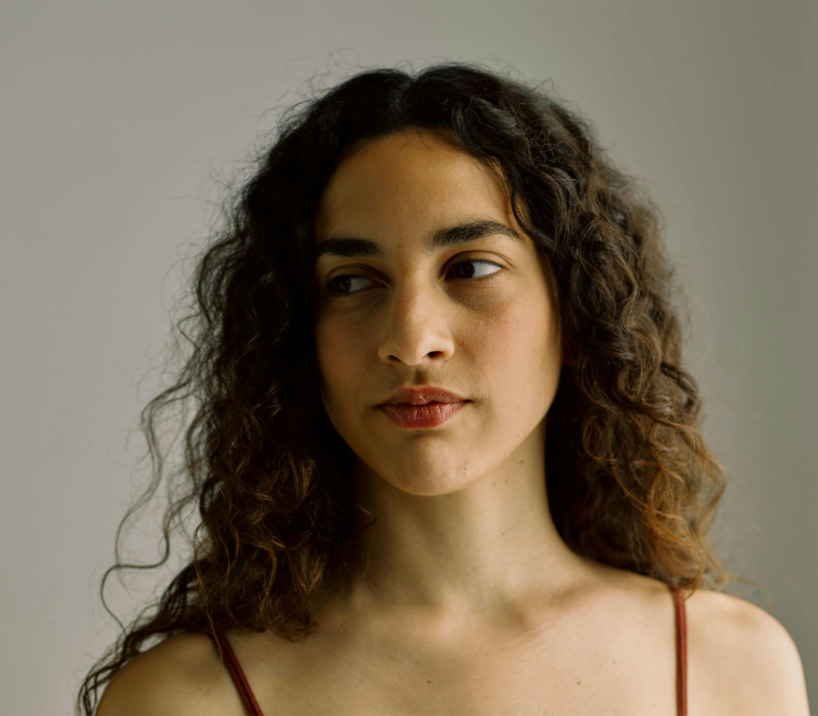 woman with curly hair looking to the left