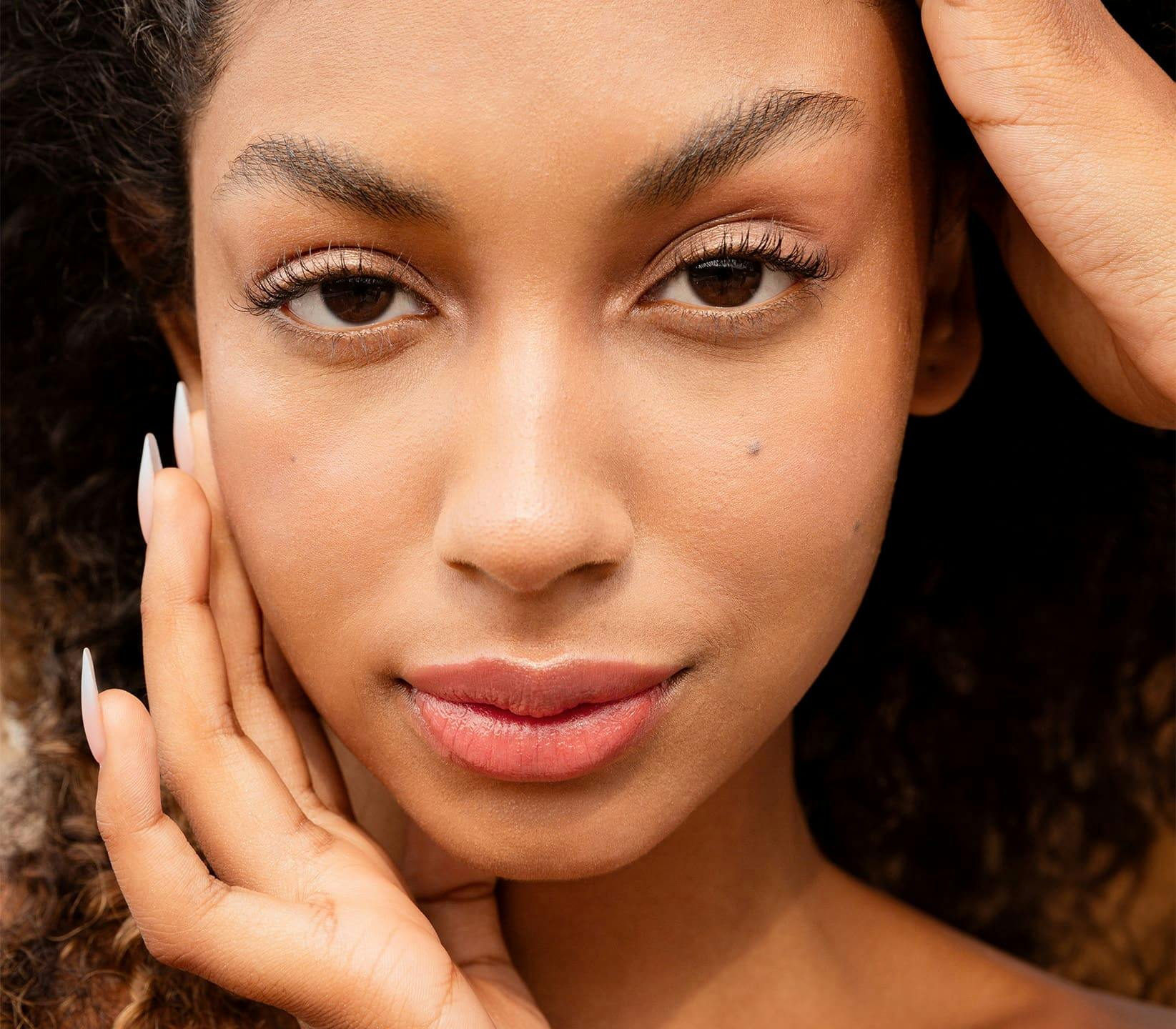 close up on woman's face while she touches her cheek