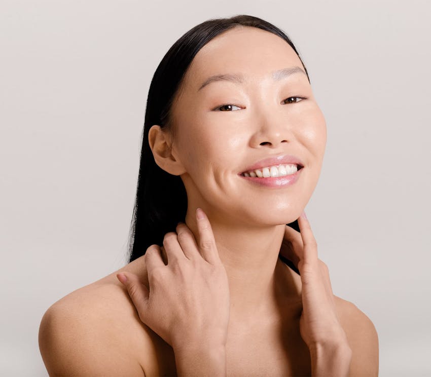 asian woman smiling with her hands on her neck