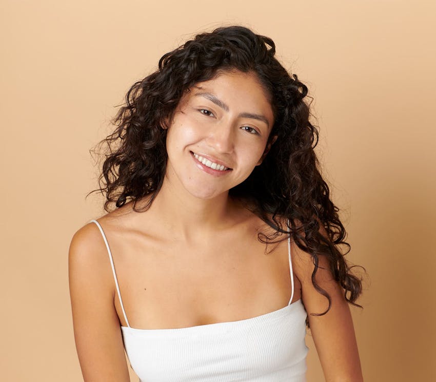 woman with curly hair in white tanktop