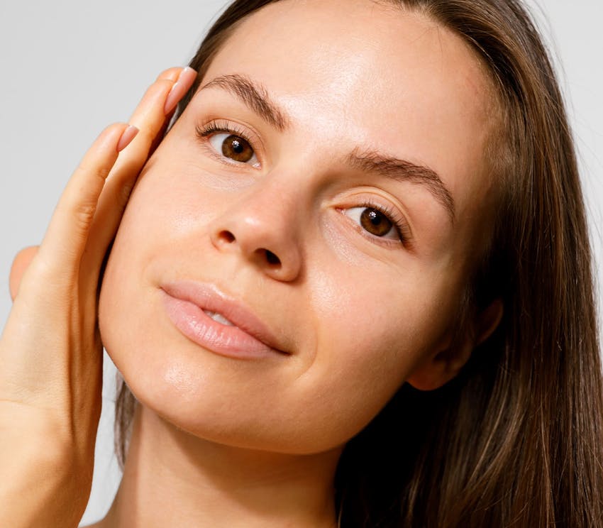 close up of woman touching her face with the back of her hand