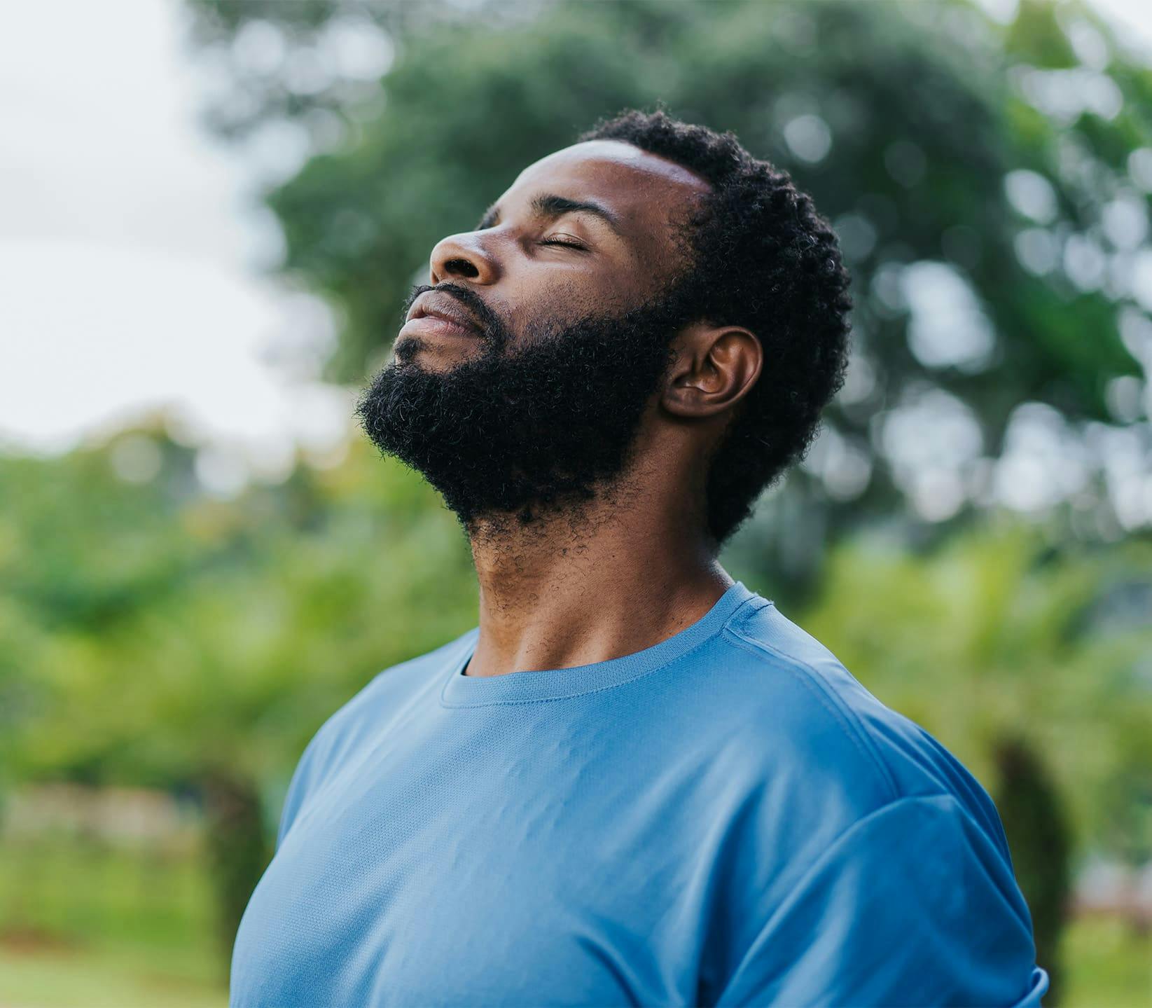 man outdoors with his head tilted up with his eyes closed