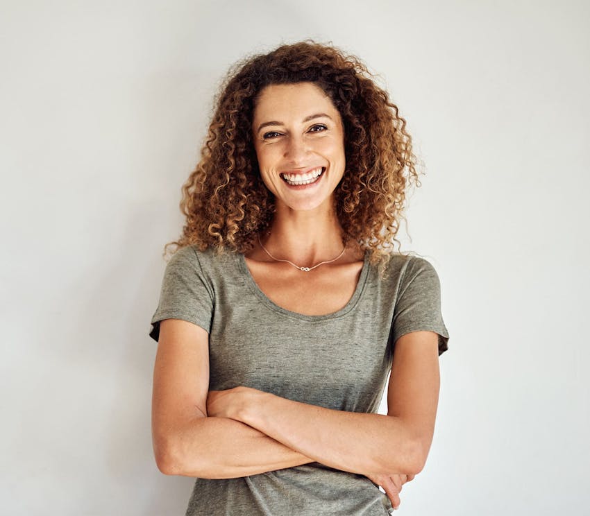 woman with curly hair smiling with arms crossed