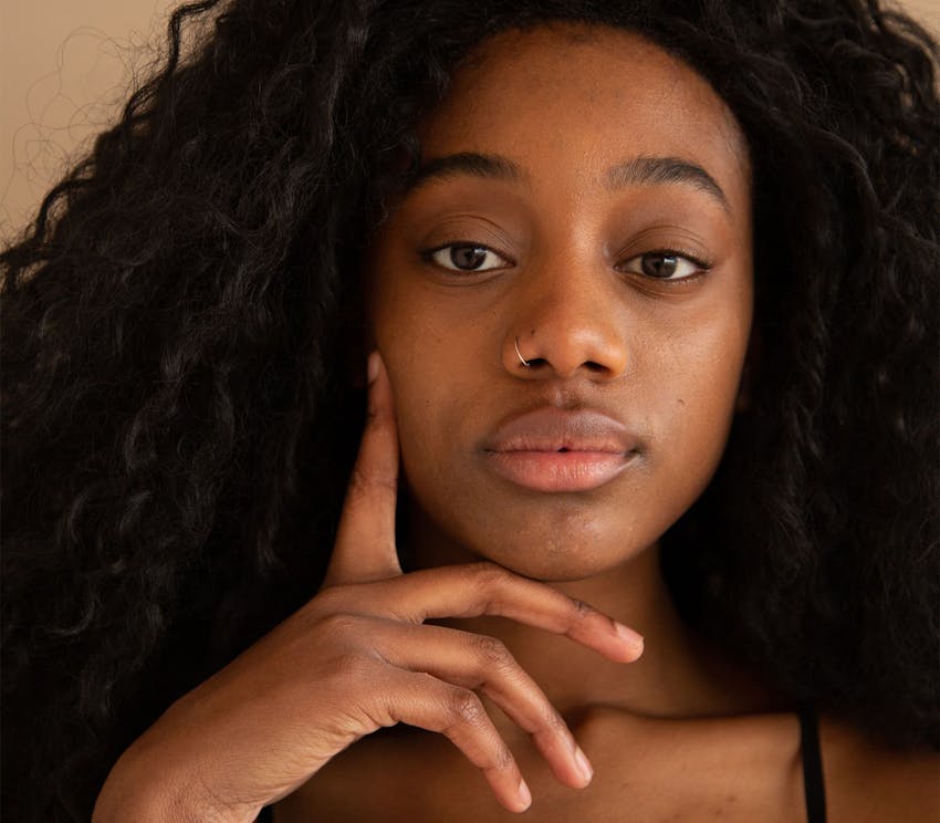 african american woman looking forward with her finger touching her cheek