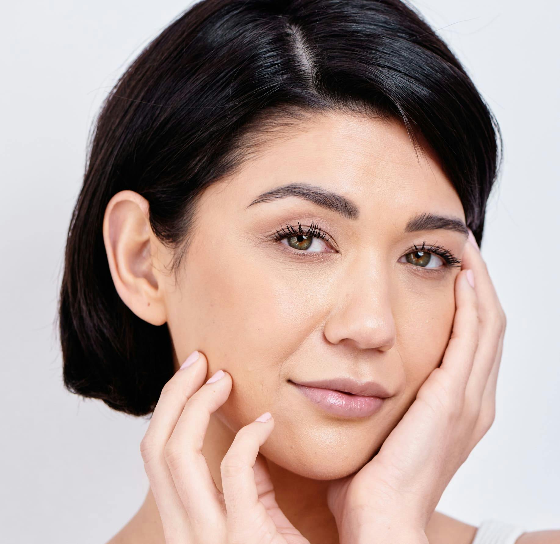 woman with short hair touching her face