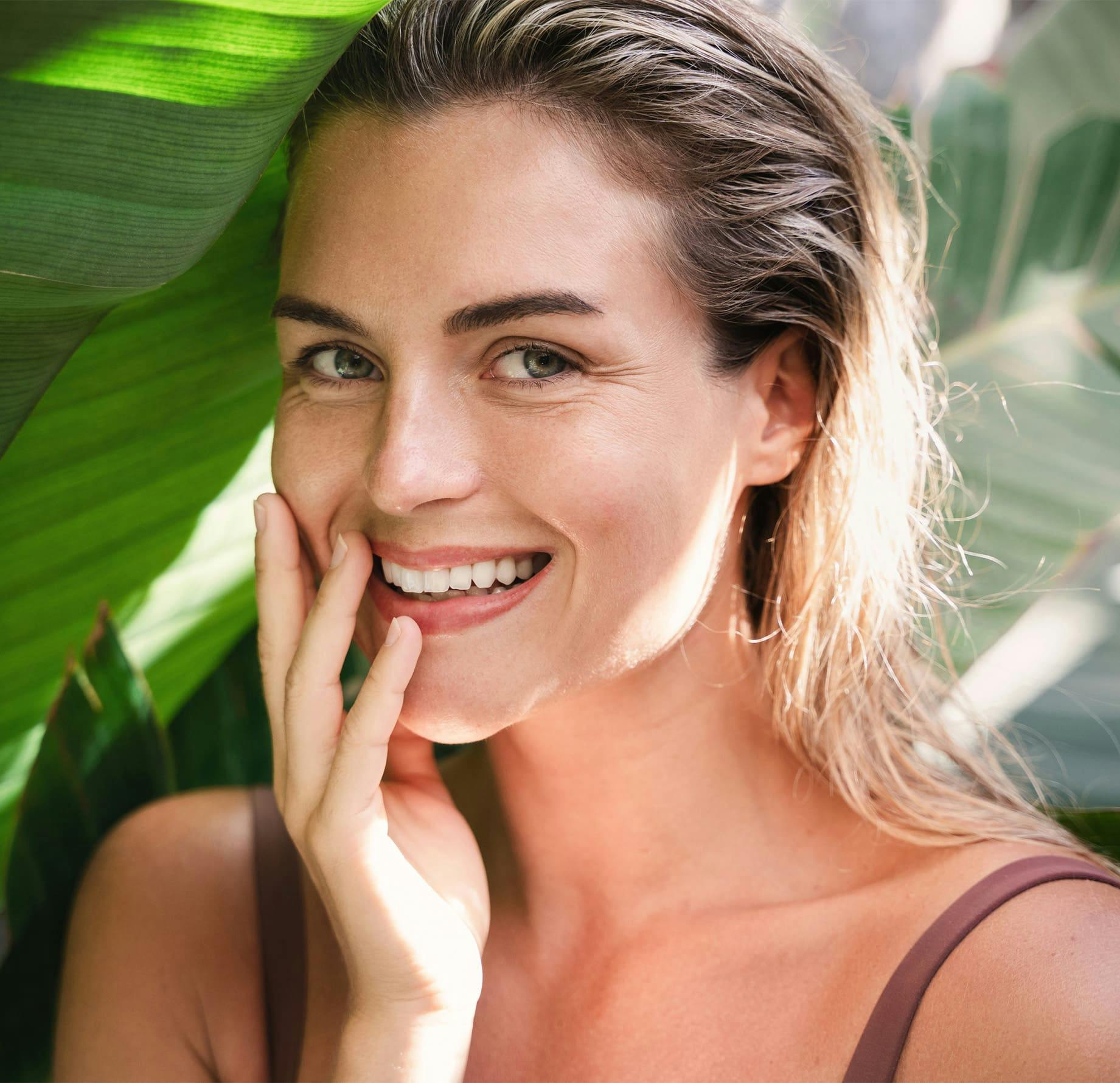 woman smiling with hand near her mouth