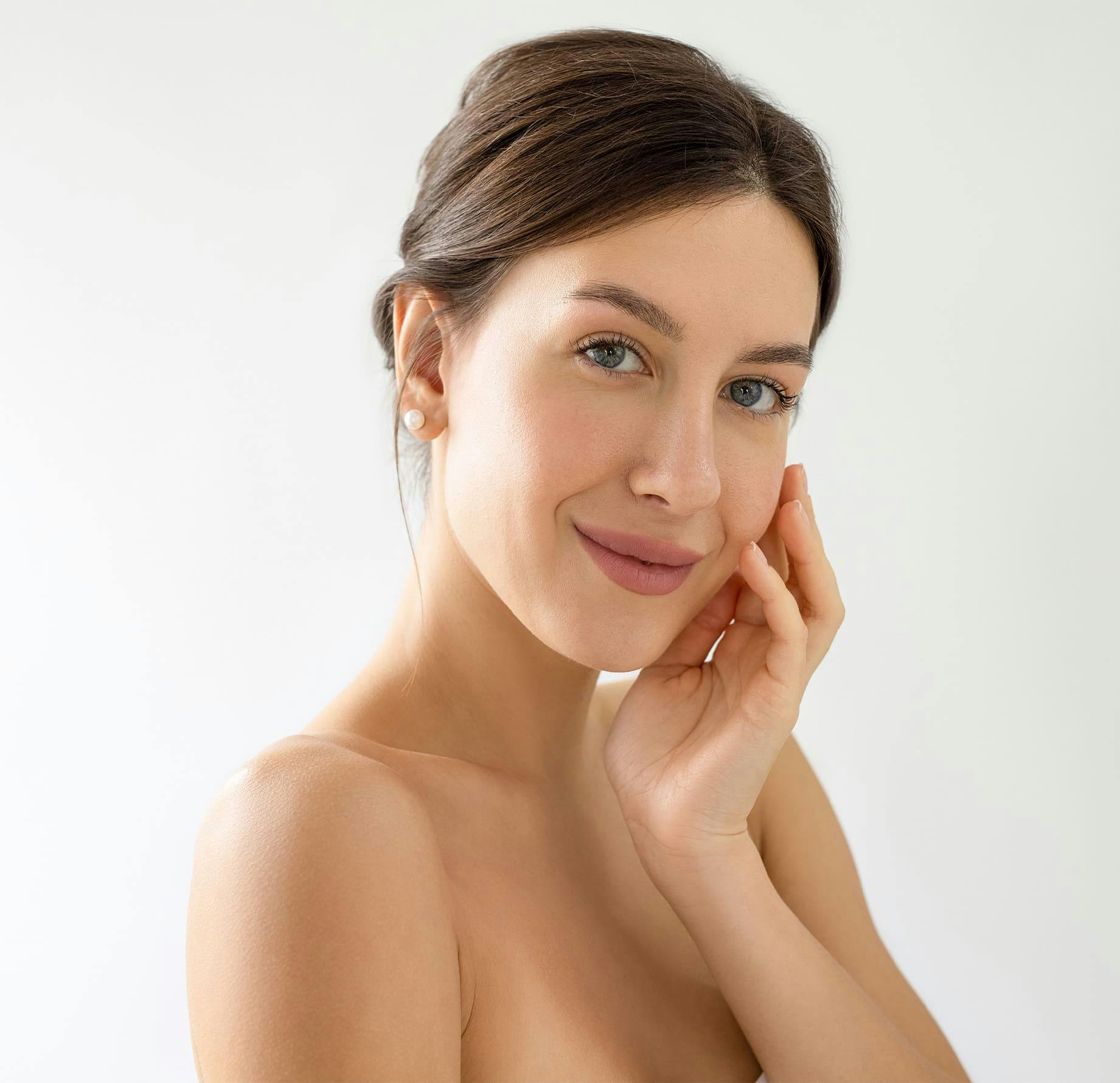 woman with her hair tied up with hand near her face