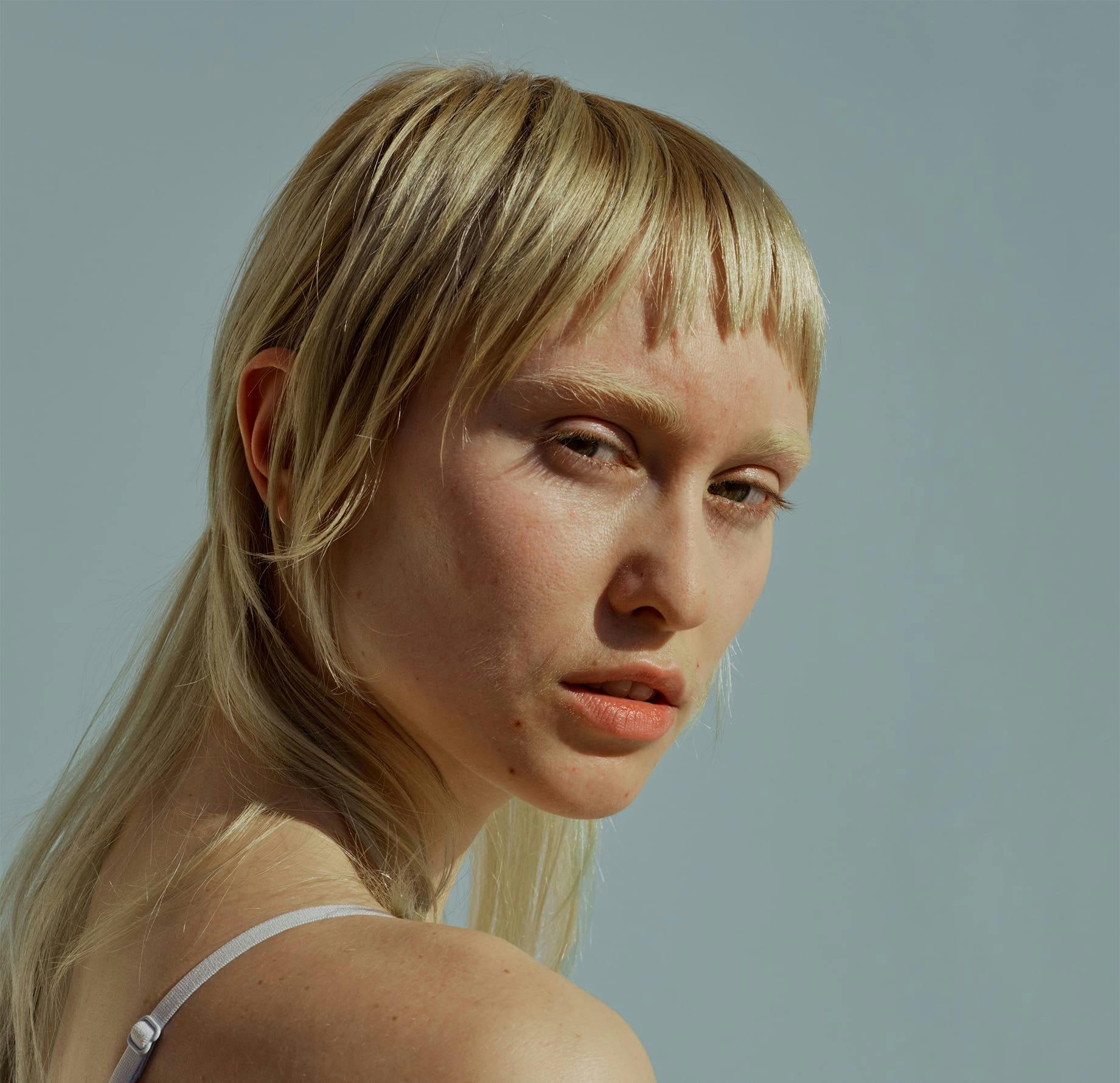 woman with micro bangs looking over her shoulder