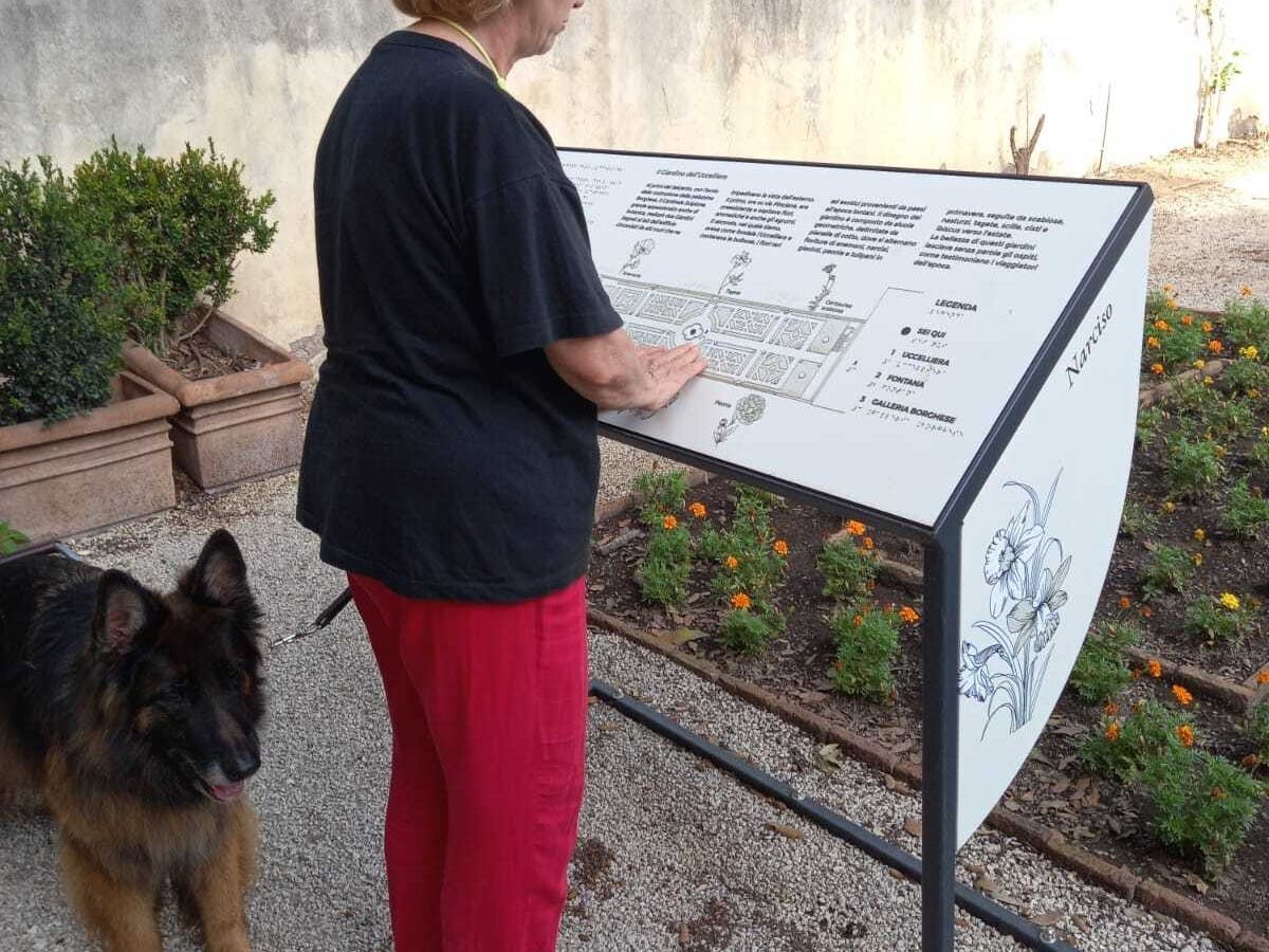 Rome, Galleria Borghese. Tactile map exploration. Rome, Galleria Borghese. Woman exploring a tactile map with her guide dog.