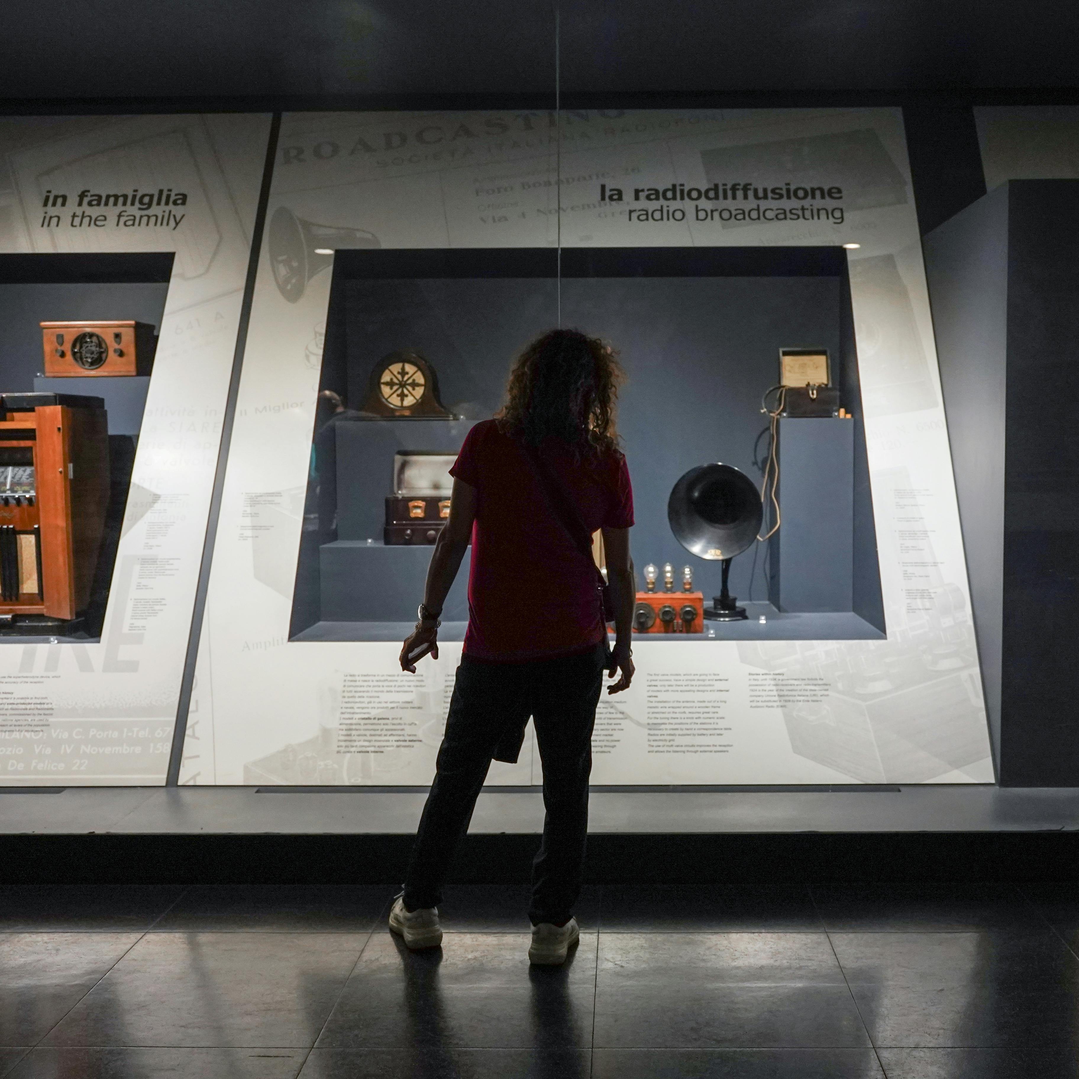 Milano, Museo della Scienza e della Tecnologia Leonardo da Vinci. Esposizione permanente "Telecomunicazioni", sulla storia ed evoluzione dei sistemi di comunicazione. Milano, Museo della Scienza e della Tecnologia Leonardo da Vinci. Esposizione permanente "Telecomunicazioni". Un ragazzo di spalle davanti ad alcuni strumenti di radiodiffusione.