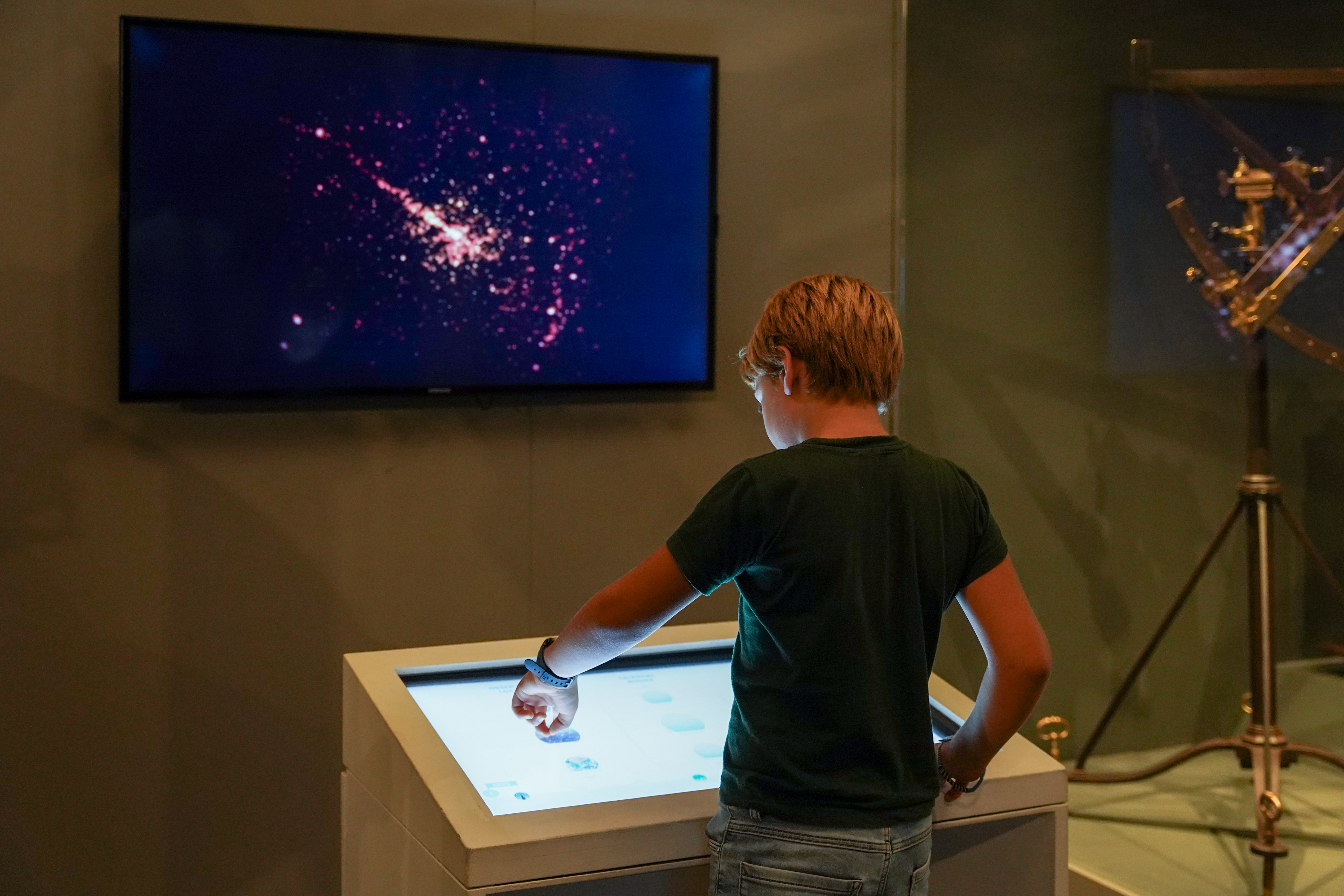 Milano, Museo della Scienza e della Tecnologia Leonardo da Vinci. Esposizione permanente "Spazio". Un bambino di spalle esplora su uno schermo delle immagini dello spazio, attraverso un tavolo interattivo digitale.