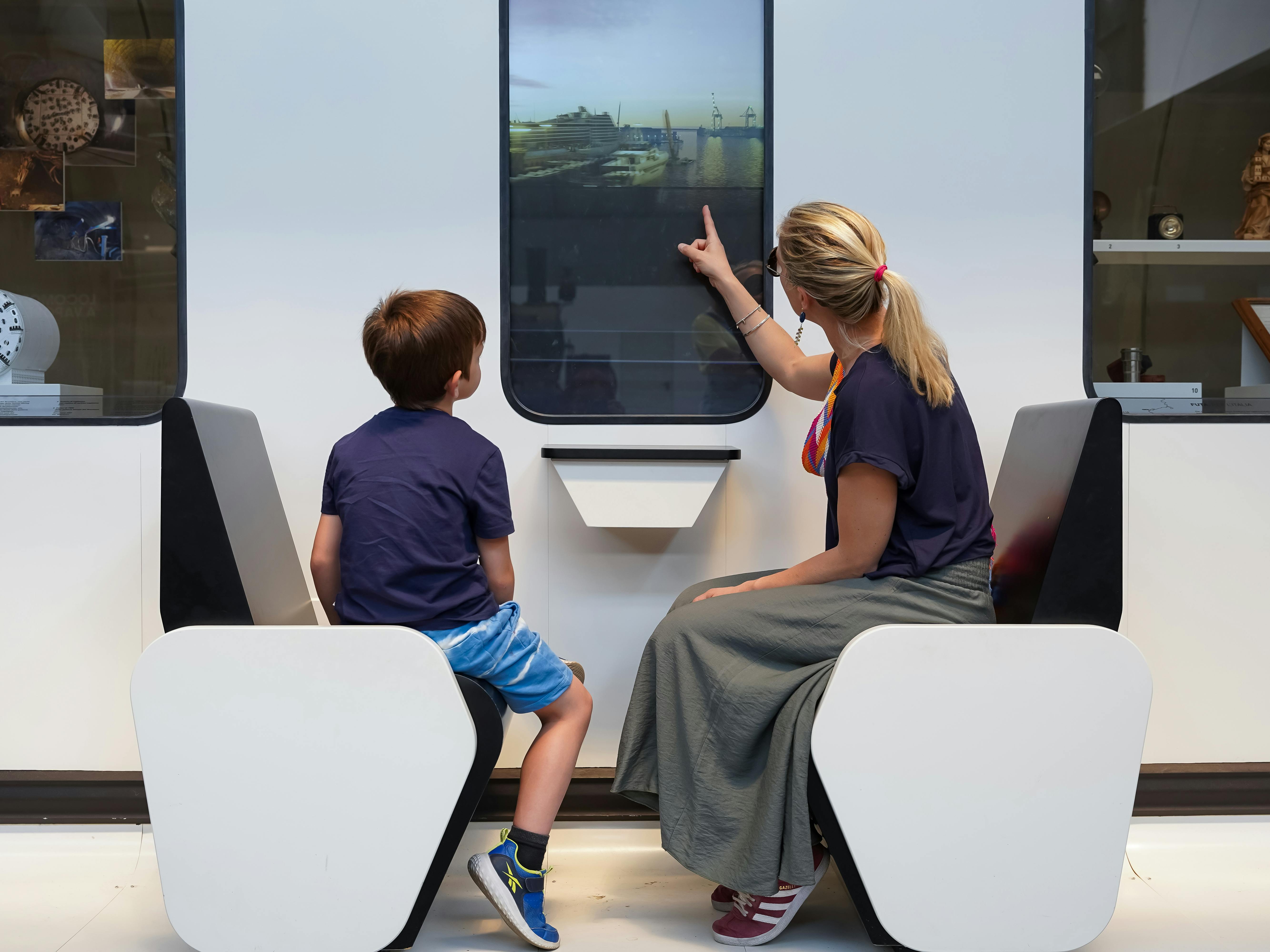 Milano, Museo della Scienza e della Tecnologia Leonardo da Vinci. Esposizione permanente "Oltrepassare", sui sistemi di trasporto ferroviari. Milano, Museo della scienza e della Tecnologia. Una donna e un bambino guardano attraverso una installazione che simula il finestrino di un treno. Esposizione "Oltrepassare", sulle infrastrutture e sui sistemi di trasporto ferroviari.
