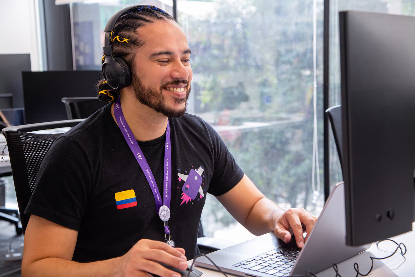 A man works at a computer in the office while wearing a headset.
