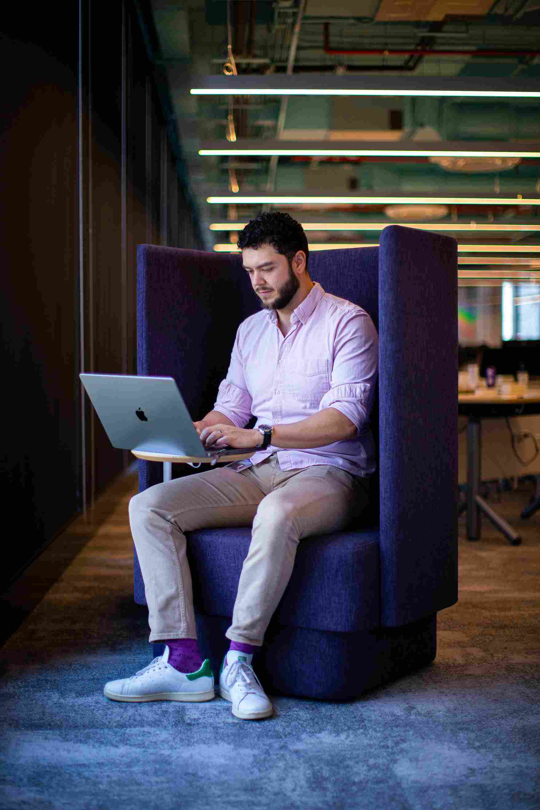 Man focusing on his laptop inside a purple office pod.
