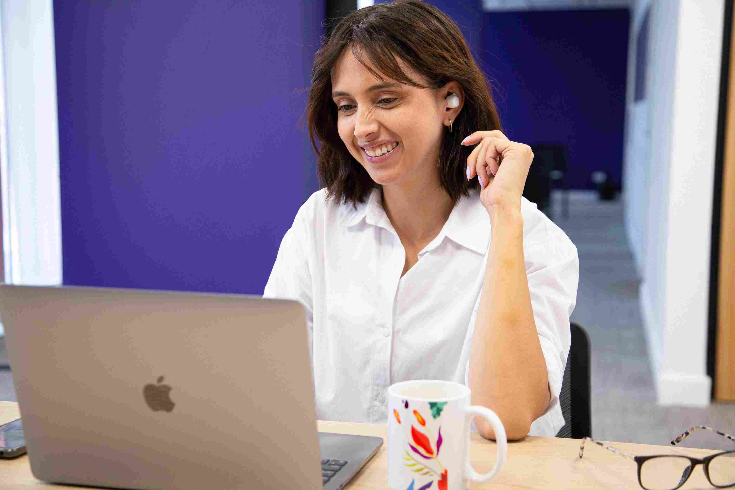 Smiling woman using her laptop at a clean office desk.