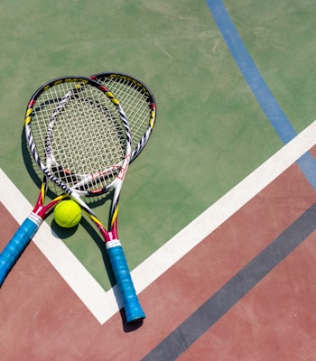 Sofitel The Palm Two tennis rackets and a ball on a court