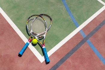 Two tennis rackets and a ball on a court