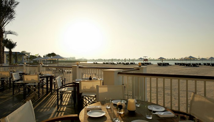 The St. Regis Abu Dhabi Beachfront dining area with tables set for a sunset view.