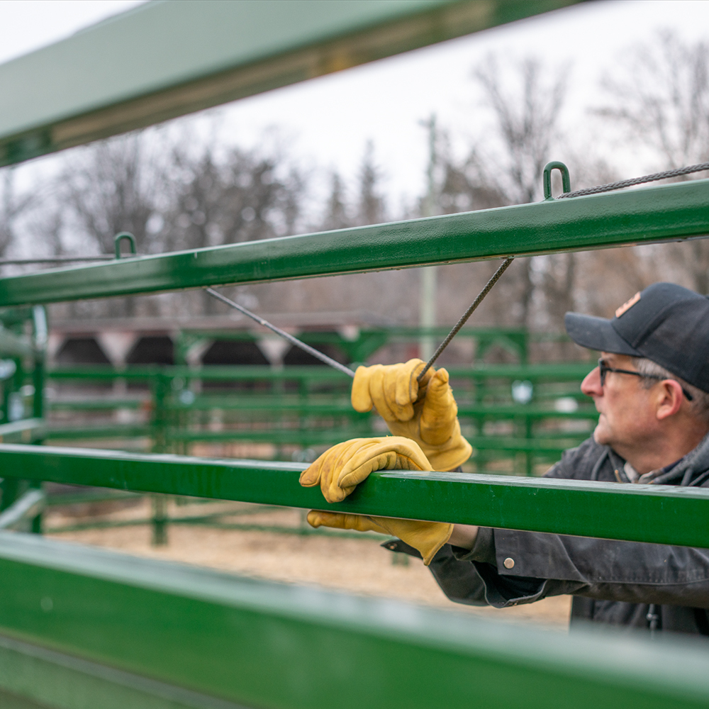 Rancher using the rope on the Easy Flow Elite Alley to easily adjust the alley width