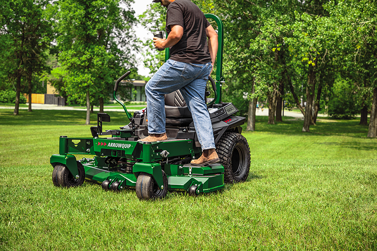 Operator standing on Arrowquip 720 commercial zero-turn mower designed for rugged performance