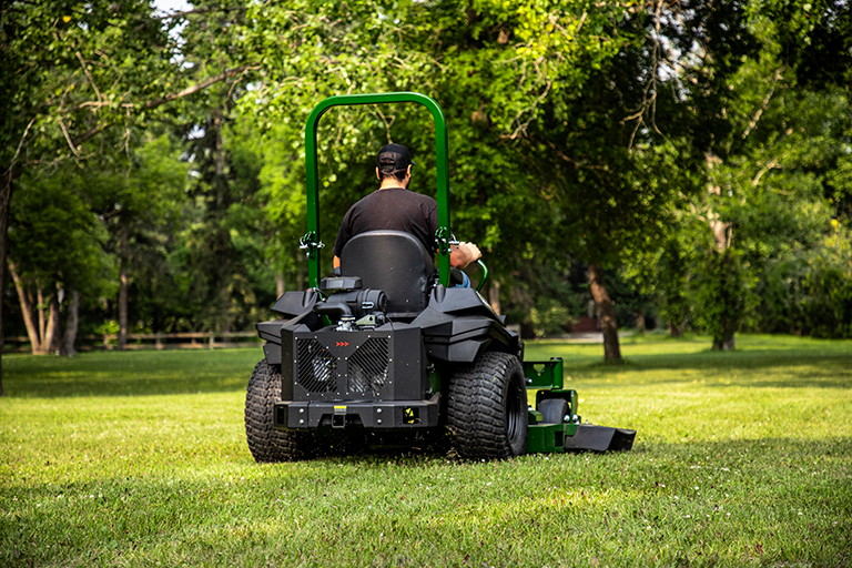 Operator mowing lawn with Arrowquip 720 commercial zero-turn mower, rear view in use