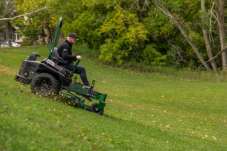 Arrowquip 720 commercial zero-turn mower cutting grass on hillside terrain with control