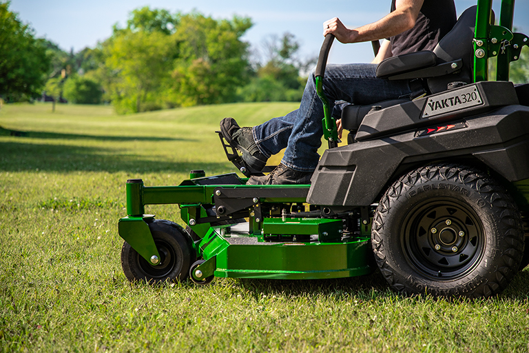 Operator using foot pedal controls on Arrowquip Mowers zero-turn mower for easy deck adjustment