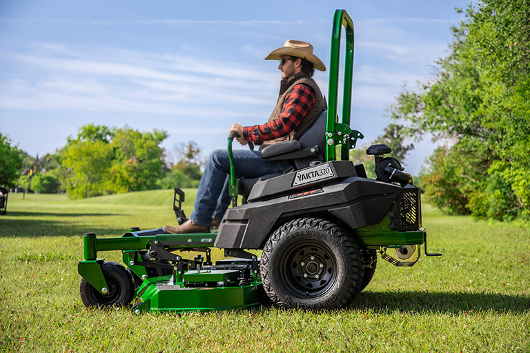 Operator in cowboy hat and boots mowing grass with Arrowquip Mowers zero-turn, engineered for durability and precise lawn care