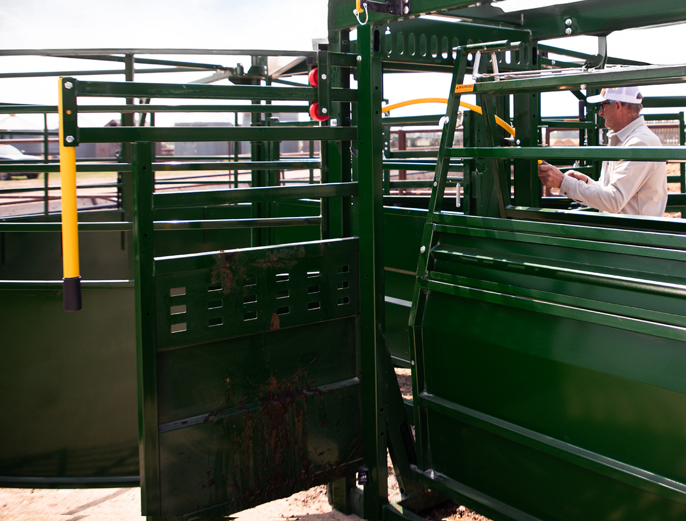 Male rancher using rolling alley gate between cattle tub and alley on portable cattle handling system