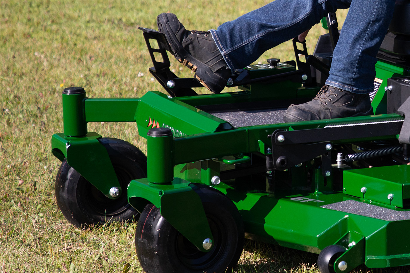 Close-up of Arrowquip zero-turn mower foot pedals and caster wheels built for strength and easy control