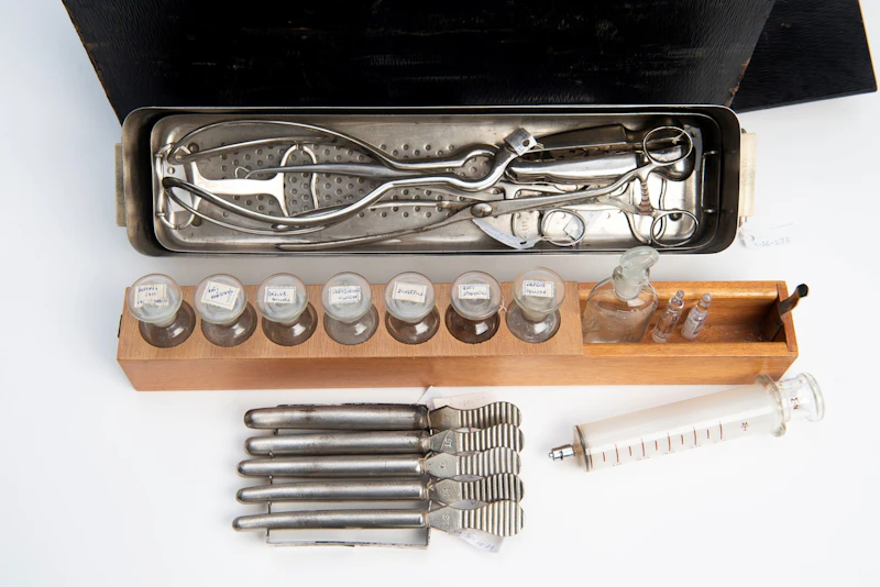Close up of black home birth kit with some instruments drawers pulled out, containing various instruments.