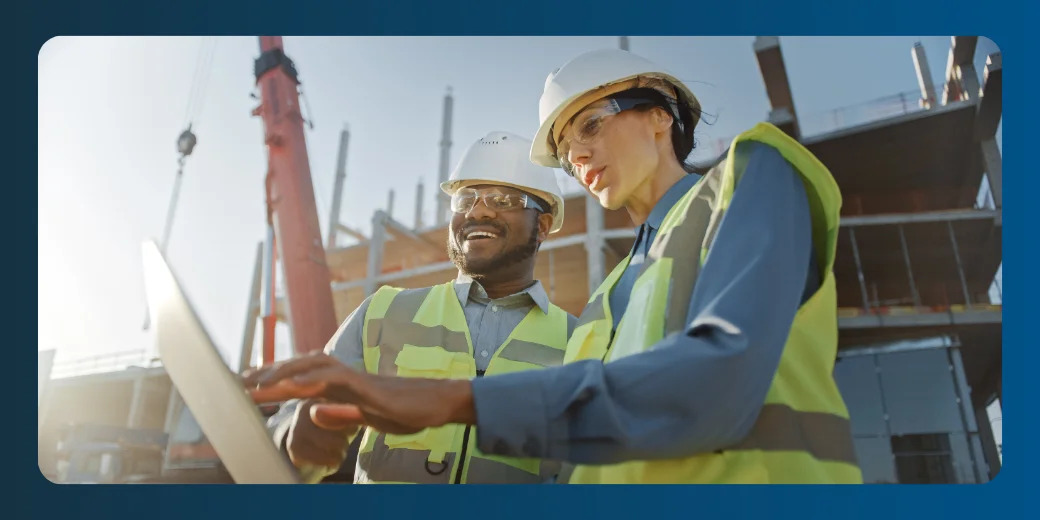 Construction workers using a laptop at a building site.