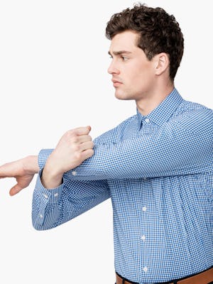 Men's Blue Gingham Aero Dress Shirt on Model Facing Forward with Arm Stretched Across Chest