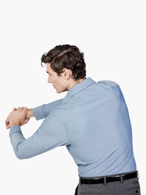 Men’s Sky Blue Oxford Brushed Apollo Dress Shirt model facing backward with arms stretched and hands clasped to the left