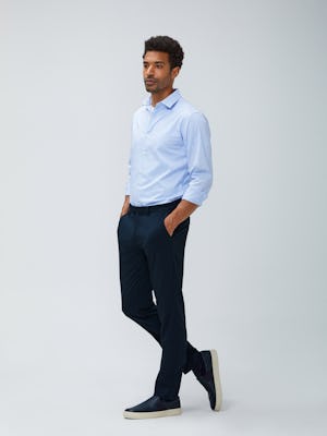 Men's sky blue grid aero dress shirt and navy kinetic pant model facing to the side with hands in pockets