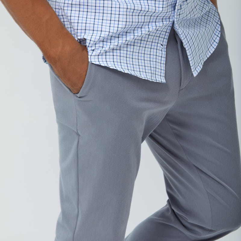 Close up of Men's Blue Tattersall Aero Zero Dress Shirt and Men's Light Grey Momentum Chino on model with hand in pants pocket