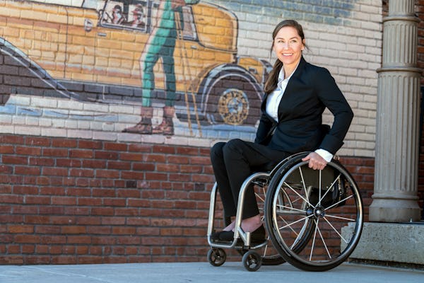 Alana Nichols, paralympian, wearing the Kinetic suit while seated in a wheelchair next to a brick wall.