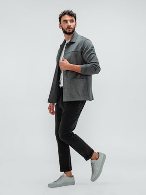 Man wearing the Momentum Tapered Chino Black, Composite Short Sleeve Tee Pale Grey Heather, and Fusion Chore Coat Charcoal with grey sneakers