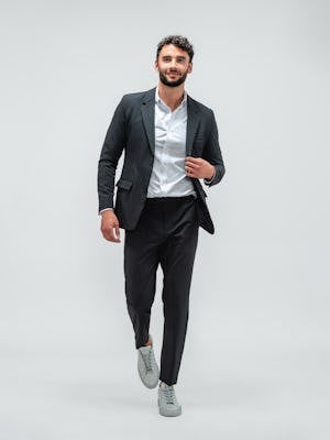 Man wearing Velocity Pant Dark Charcoal, Hybrid Button Down Grey Stripe, Velocity Blazer Dark Charcoal and grey sneakers