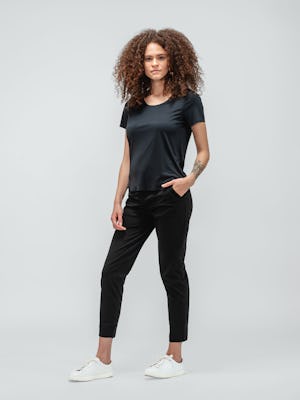 Woman with curly hair wearing black short sleeve luxe touch tee and black kinetic pull on pants and white sneakers