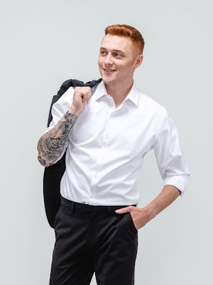 close up of model wearing men's black wool velocity merino suit and white aero zero dress shirt facing forward with hand in pocket