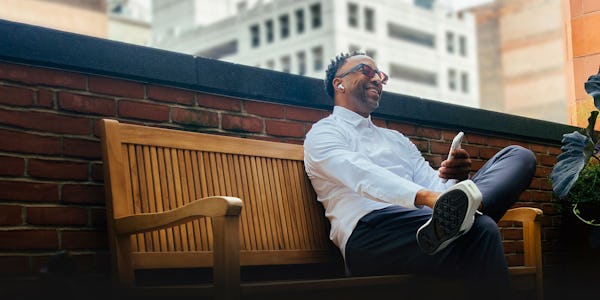 man sitting on a bench using his phone wearing a white aero zero dress shirt