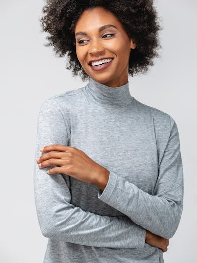 model wearing women's pale grey heather composite merino mock neck facing forward with arms crossed