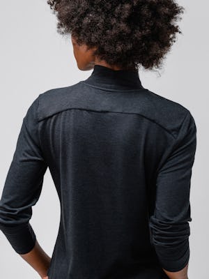 close up of model wearing black composite merino mock neck facing away with sleeves pulled up