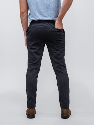 model wearing men's navy tweed fusion pant and composite merino active tee facing away with hand in back pocket