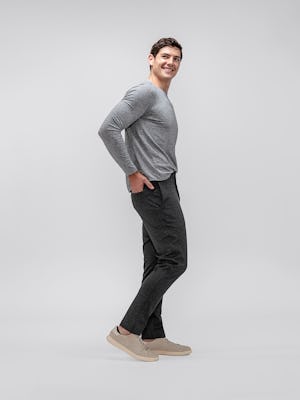 model wearing men's charcoal heather fusion pant and composite merino long sleeve tee facing to the side with hand in rear pocket