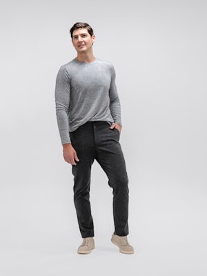 model wearing men's pale grey heather composite merino long sleeve tee and charcoal fusion pant facing forward with hand in pocket